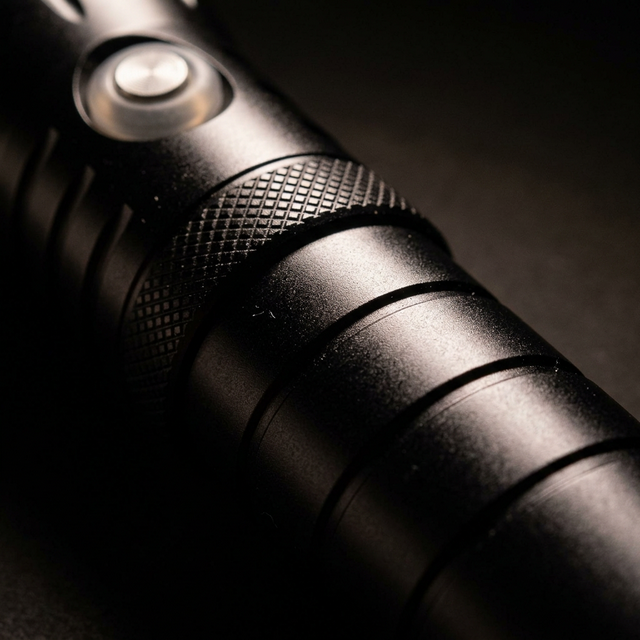 Vista lateral de la linterna PS Dive SMALL 2000 mostrando el perfil completo con el pulsador y el aro dorado