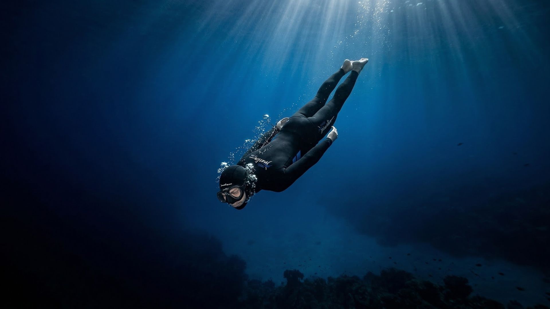 Apneísta descendiendo en caída libre en el mar abierto hacia la profundidad